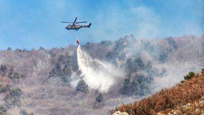 Na težko dostopnih območjih, kjer še gori, gasijo s helikopterjem Slovenske vojske (LEO CAHARIJA/PRIMORSKE NOVICE)