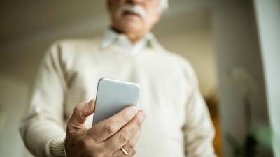 Starejša oseba s pametnim telefonom, fotografija je simbolična (MAGNIFIC)