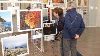 Obiskovalki si ogledujeta fotografije na razstavi (BUMBACA)