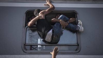 Fotografija o migrantu, ki se skuša vkrcati na vlak; smer Zagreb