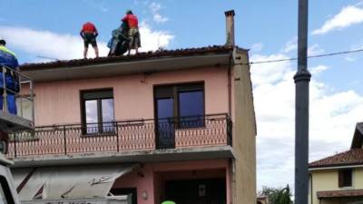 Prostovoljci civilne zaščite hitijo s prekrivanjem poškodovanih streh