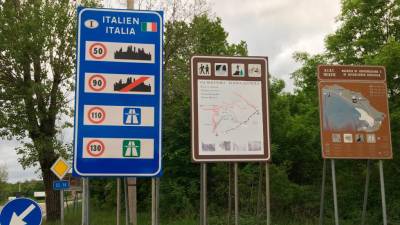 Dvojezična tabla v nemščini in italijanščini ob dveh turističnih tablah na Pesku (MLIS)