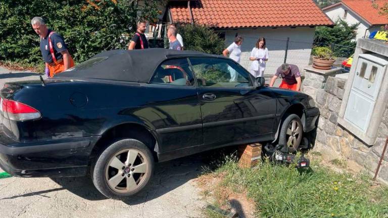 Umrl pod vozilom, ki ga je stisnilo ob zid